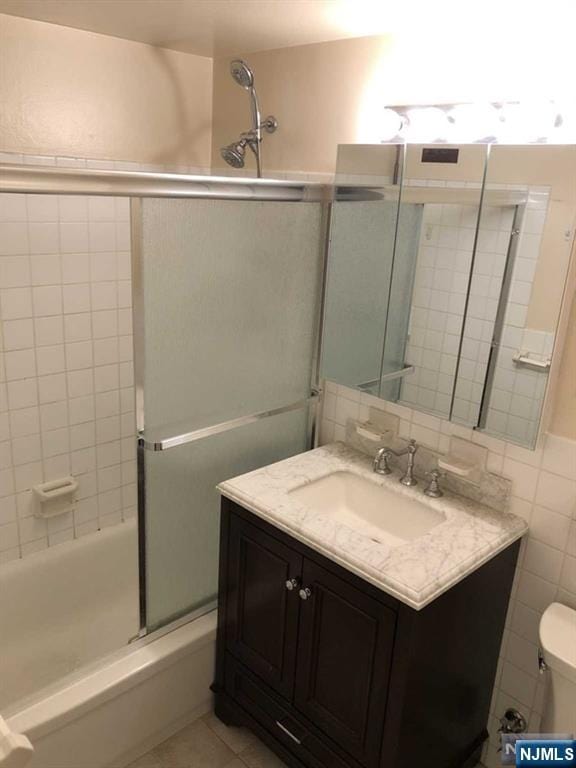 285 Aycrigg Ave Unit 22D, Passaic, NJ 07055 - bathroom featuring tile walls, vanity, bath / shower combo with glass door, and tile patterned flooring