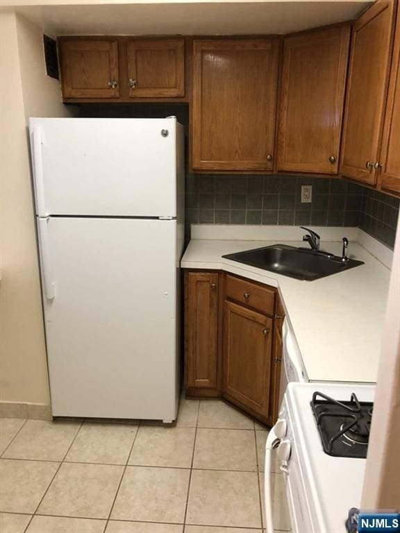 285 Aycrigg Ave Unit 22D, Passaic, NJ 07055 - kitchen with white appliances, light countertops, light tile patterned floors, brown cabinets, and tasteful backsplash