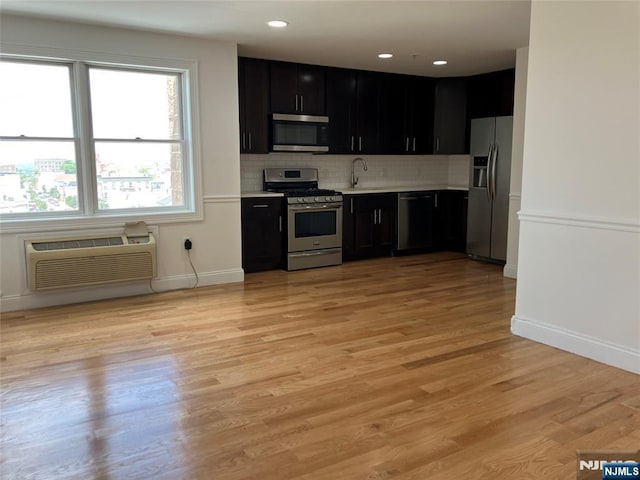 315 7th St Unit 702, Union City, NJ 07087 - kitchen featuring appliances with stainless steel finishes, dark cabinetry, a wall unit AC, light countertops, and backsplash