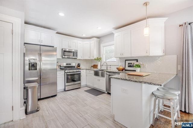 20 Brighton Ave, Bloomfield, NJ 07003 - kitchen featuring stainless steel appliances, a peninsula, light stone countertops, white cabinetry, and tasteful backsplash