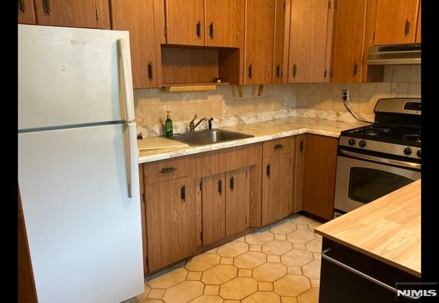 67 Melody Hill Rd, Clifton, NJ 07013 - kitchen featuring freestanding refrigerator, gas stove, under cabinet range hood, and light countertops
