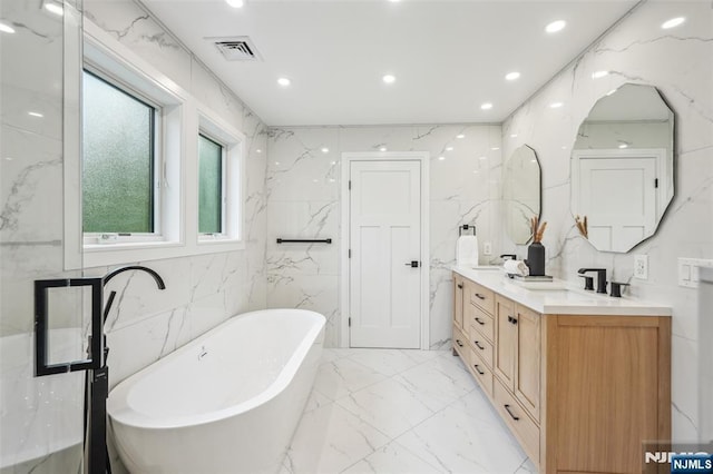 492 Oaktree Rd, Oradell, NJ 07649 - bathroom featuring double vanity, a freestanding bath, marble finish flooring, tile walls, and recessed lighting