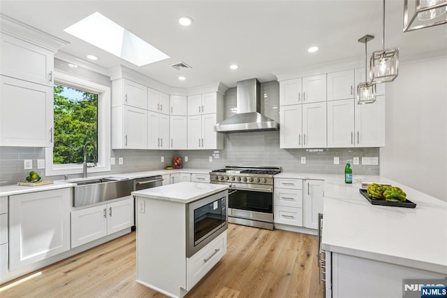 492 Oaktree Rd, Oradell, NJ 07649 - kitchen featuring wall chimney range hood, appliances with stainless steel finishes, a skylight, tasteful backsplash, and white cabinetry