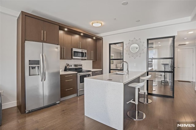6401 Park Ave Unit 401, West New York, NJ 07093 - kitchen featuring appliances with stainless steel finishes, dark wood-style floors, dark brown cabinets, a kitchen breakfast bar, and a kitchen island with sink