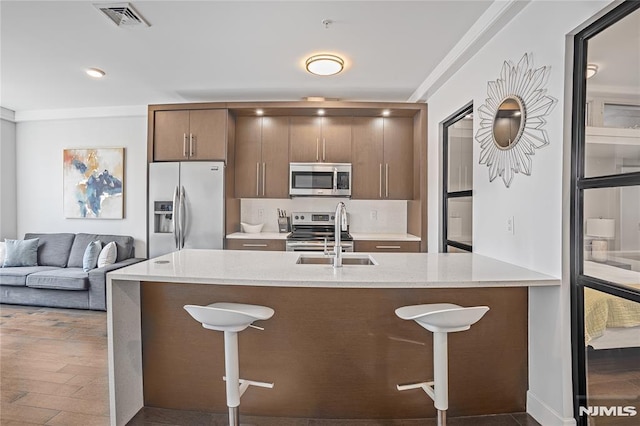 6401 Park Ave Unit 401, West New York, NJ 07093 - kitchen featuring appliances with stainless steel finishes, a breakfast bar area, dark wood-style flooring, light stone countertops, and ornamental molding