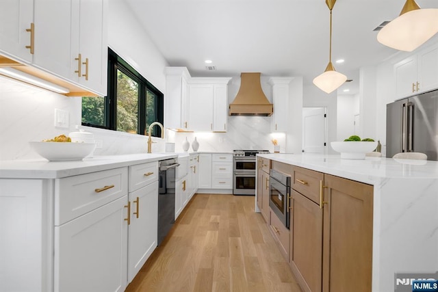 452 Oregon St, Paramus, NJ 07652 - kitchen featuring premium range hood, stainless steel appliances, light wood-style flooring, a center island, and white cabinets