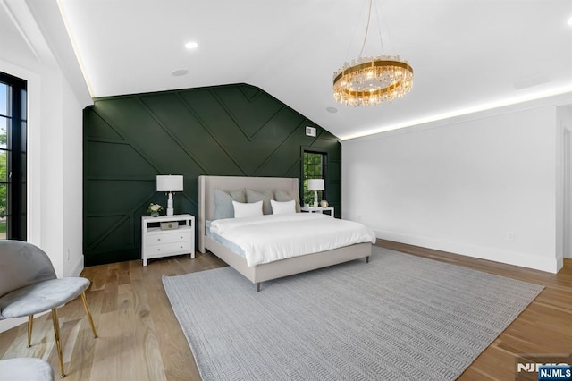 452 Oregon St, Paramus, NJ 07652 - bedroom featuring multiple windows, vaulted ceiling, a chandelier, wood finished floors, and a decorative wall