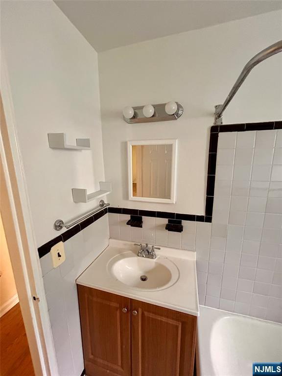 2195 N Central Rd Unit 4H, Fort Lee, NJ 07024 - full bath featuring vanity, tile walls, and  shower combination