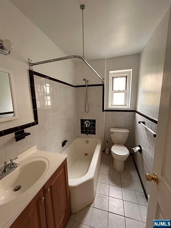 2195 N Central Rd Unit 4H, Fort Lee, NJ 07024 - bathroom featuring tile walls, vanity, shower / tub combination, tile patterned floors, and wainscoting