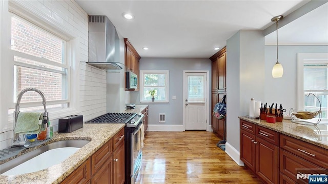 39 Boyden Pkwy, Maplewood, NJ 07040 - kitchen featuring appliances with stainless steel finishes, wall chimney exhaust hood, light wood-style floors, pendant lighting, and backsplash