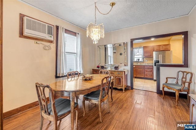 1 Whittlesey Ave, West Orange, NJ 07052 - dining space with a wall mounted AC, a chandelier, light wood-type flooring, and a textured ceiling