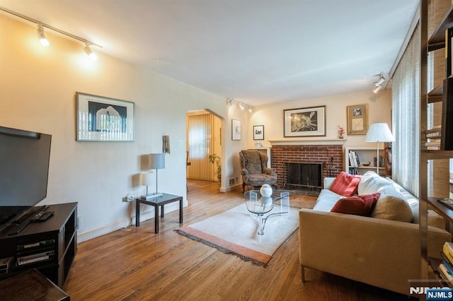 279 Jefferson Ave, Cresskill, NJ 07626 - living room featuring rail lighting, wood finished floors, a brick fireplace, and arched walkways