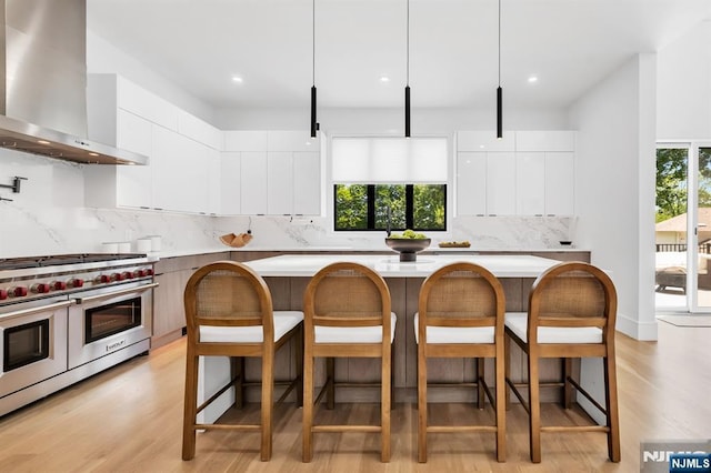404 Willard Rd, Paramus, NJ 07652 - kitchen featuring wall chimney exhaust hood, range with two ovens, modern cabinets, a kitchen bar, and recessed lighting
