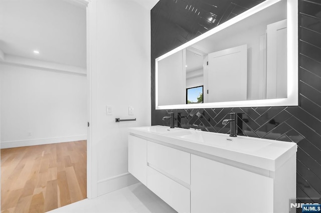 404 Willard Rd, Paramus, NJ 07652 - bathroom with double vanity, wood finished floors, backsplash, and recessed lighting