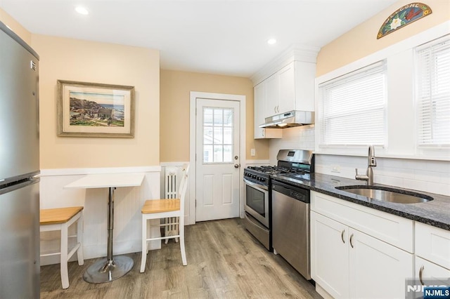 39 Lexington Ave, Bloomfield, NJ 07003 - kitchen with stainless steel appliances, under cabinet range hood, dark stone counters, light wood-type flooring, and white cabinetry