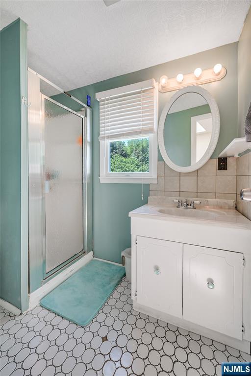 23 Bromley Pl, Bloomfield, NJ 07003 - full bathroom featuring a shower stall, vanity, tasteful backsplash, and tile patterned floors