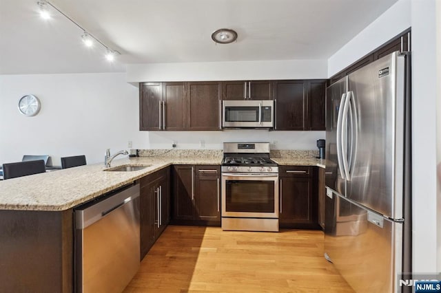 5711 Jefferson St Unit 405, West New York, NJ 07093 - kitchen featuring appliances with stainless steel finishes, dark brown cabinetry, light wood-type flooring, a peninsula, and light stone counters