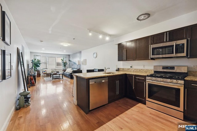 5711 Jefferson St Unit 405, West New York, NJ 07093 - kitchen featuring appliances with stainless steel finishes, light wood-style floors, a peninsula, dark brown cabinetry, and open floor plan