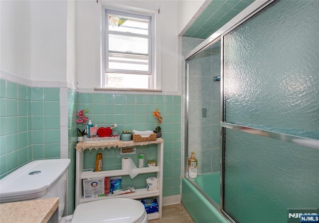 320 Clifton Ave, Newark, NJ 07104 - bathroom featuring tile walls, combined bath / shower with glass door, vanity, and wainscoting