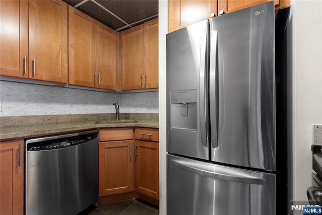 187 Wayne St Unit 405, Jersey City, NJ 07302 - kitchen with stainless steel appliances, brown cabinetry, dark tile patterned floors, and light stone counters