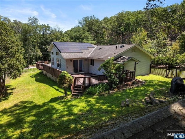 699 Shore Rd, West Milford, NJ 07421 - rear view of property featuring solar panels, a shingled roof, a wooden deck, a fenced backyard, and a view of trees