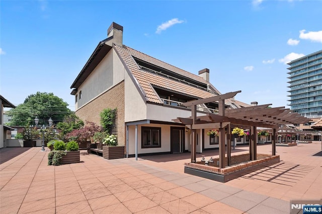 300 Gorge Rd Unit 1, Cliffside Park, NJ 07010 - back of property with stucco siding, a pergola, a patio, a chimney, and a balcony