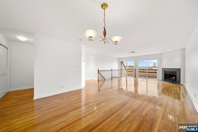 300 Gorge Rd Unit 1, Cliffside Park, NJ 07010 - unfurnished living room with a chandelier, light wood-type flooring, and a warm lit fireplace