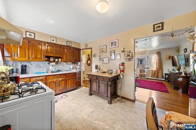 67 6th Ave, Passaic, NJ 07055 - kitchen featuring white range with gas cooktop, ventilation hood, light countertops, brown cabinets, and backsplash