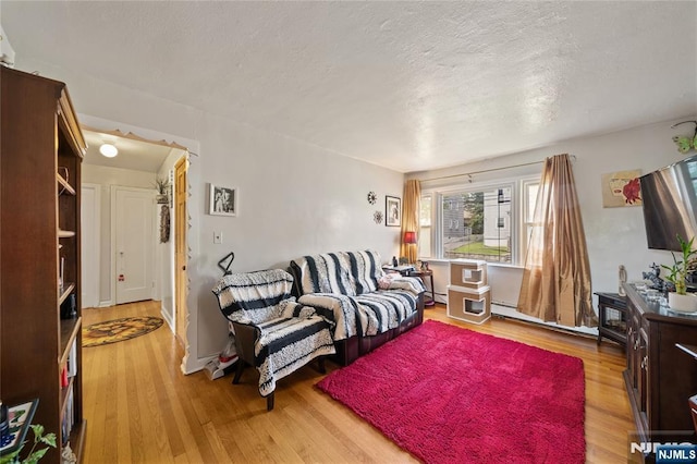 67 6th Ave, Passaic, NJ 07055 - living area featuring wood finished floors, a textured ceiling, and a baseboard radiator