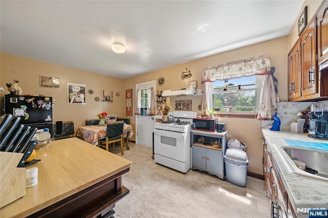 67 6th Ave, Passaic, NJ 07055 - kitchen featuring black appliances, light countertops, under cabinet range hood, brown cabinets, and decorative backsplash