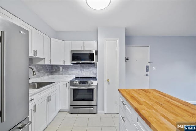 412-432 Broadway Unit 25A, Passaic, NJ 07055 - kitchen featuring appliances with stainless steel finishes, butcher block countertops, light tile patterned floors, white cabinets, and tasteful backsplash