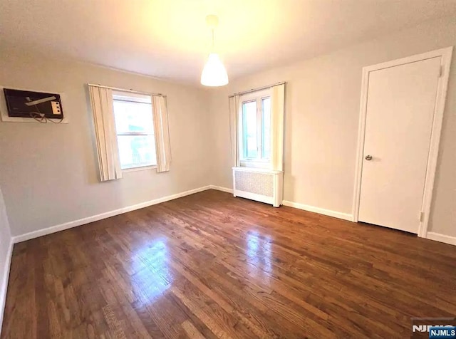 137 Prospect St, Lodi, NJ 07644 - unfurnished bedroom with multiple windows, dark wood-style floors, and radiator heating unit