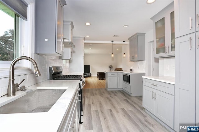 8 Cedar Rd, Dumont, NJ 07628 - kitchen with stainless steel appliances, backsplash, glass insert cabinets, recessed lighting, and light wood-style floors