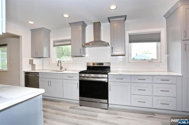 8 Cedar Rd, Dumont, NJ 07628 - kitchen featuring wall chimney exhaust hood, appliances with stainless steel finishes, gray cabinets, decorative backsplash, and light wood finished floors