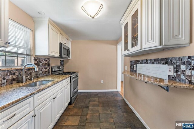 837 Keep St, Linden, NJ 07036 - kitchen featuring stainless steel appliances, decorative backsplash, glass insert cabinets, light stone counters, and white cabinets