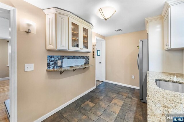 837 Keep St, Linden, NJ 07036 - kitchen with freestanding refrigerator, glass insert cabinets, light stone counters, and cream cabinets