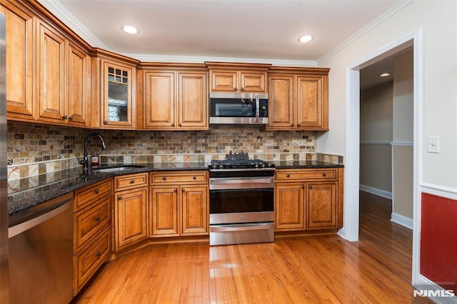 29 Concord Rd Unit F, West Milford, NJ 07480 - kitchen featuring appliances with stainless steel finishes, brown cabinetry, light wood-style floors, ornamental molding, and glass insert cabinets