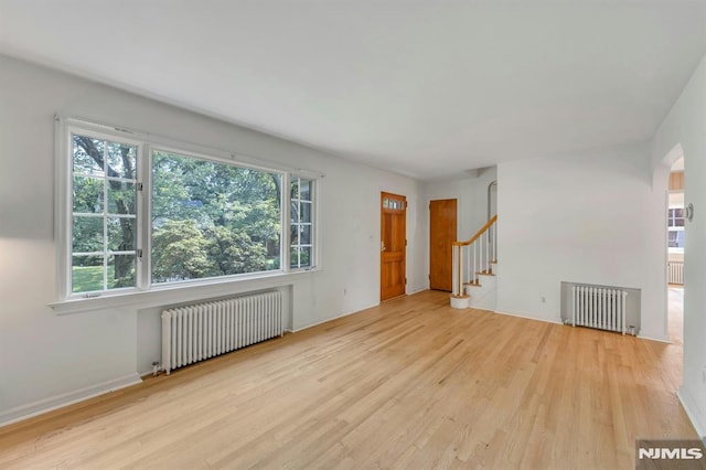 33 Ravine Dr, Hawthorne, NJ 07506 - unfurnished living room with radiator, wood finished floors, and plenty of natural light