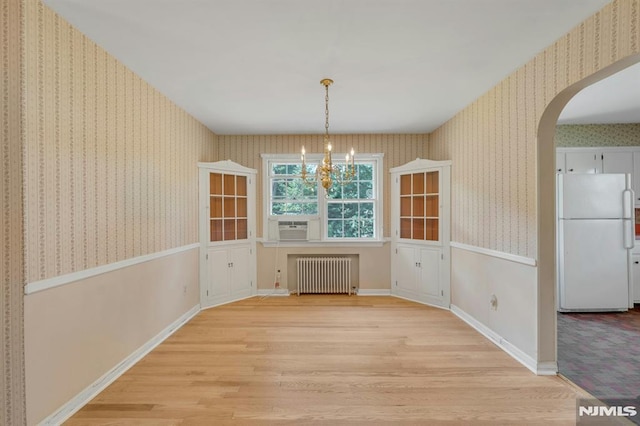 33 Ravine Dr, Hawthorne, NJ 07506 - unfurnished dining area with radiator, wallpapered walls, light wood finished floors, arched walkways, and a chandelier
