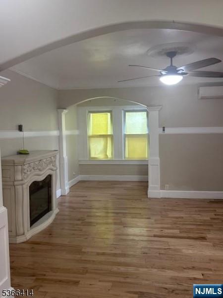 34 Voorhees St, Newark, NJ 07108 - unfurnished living room featuring a ceiling fan, a wall mounted AC, wood finished floors, and a glass covered fireplace