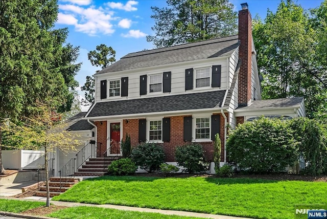 35 Hawthorne Ave, Glen Ridge, NJ 07028 - view of front facade with a chimney, a front yard, a shingled roof, and brick siding