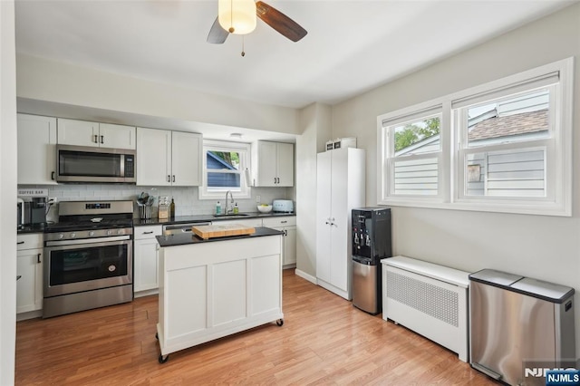 862 Lafayette Ave Extension, Hawthorne, NJ 07506 - kitchen with appliances with stainless steel finishes, radiator, dark countertops, tasteful backsplash, and light wood finished floors