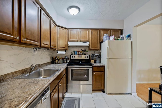 462 Liberty St Unit 109, Little Ferry, NJ 07643 - kitchen featuring appliances with stainless steel finishes, under cabinet range hood, decorative backsplash, a textured ceiling, and brown cabinets
