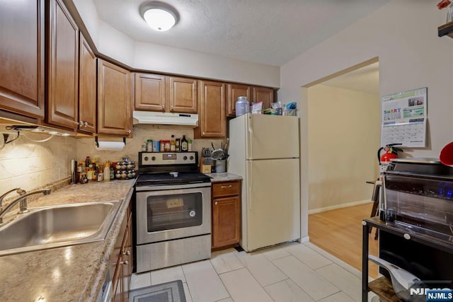 462 Liberty St Unit 109, Little Ferry, NJ 07643 - kitchen with stainless steel electric stove, freestanding refrigerator, under cabinet range hood, decorative backsplash, and brown cabinets