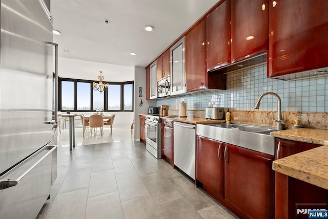 100 Carlyle Dr Unit 12K-S, Cliffside Park, NJ 07010 - kitchen featuring stainless steel appliances, backsplash, a chandelier, light tile patterned flooring, and dark brown cabinets