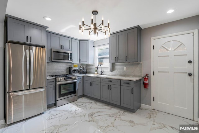 9 Westervelt Pl, Irvington, NJ 07111 - kitchen featuring stainless steel appliances, gray cabinetry, a chandelier, light marble finish floors, and backsplash