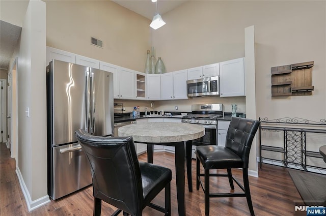1066 Ash Dr, Mahwah, NJ 07430 - kitchen with appliances with stainless steel finishes, a towering ceiling, white cabinets, glass insert cabinets, and dark wood-type flooring