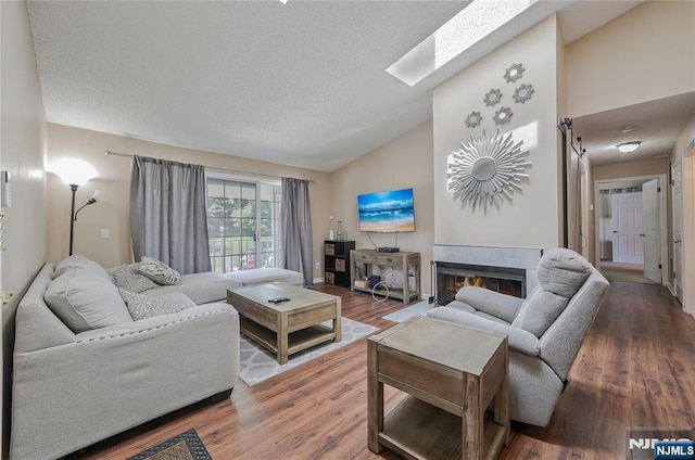 1066 Ash Dr, Mahwah, NJ 07430 - living room with vaulted ceiling, a skylight, wood finished floors, a textured ceiling, and a warm lit fireplace