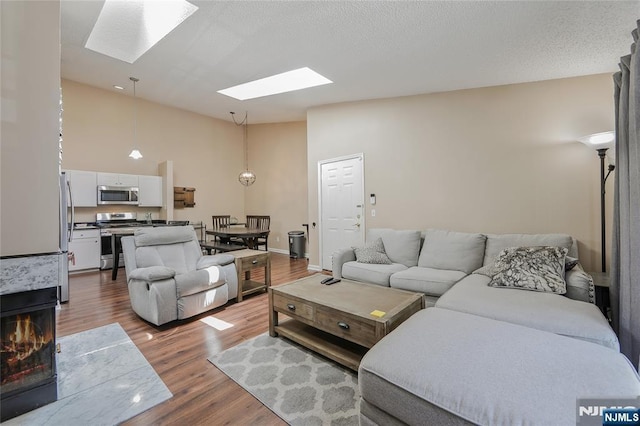 1066 Ash Dr, Mahwah, NJ 07430 - living room featuring a skylight, wood finished floors, high vaulted ceiling, and a warm lit fireplace