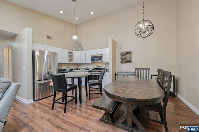 1066 Ash Dr, Mahwah, NJ 07430 - dining area featuring a towering ceiling, a chandelier, wood finished floors, and recessed lighting